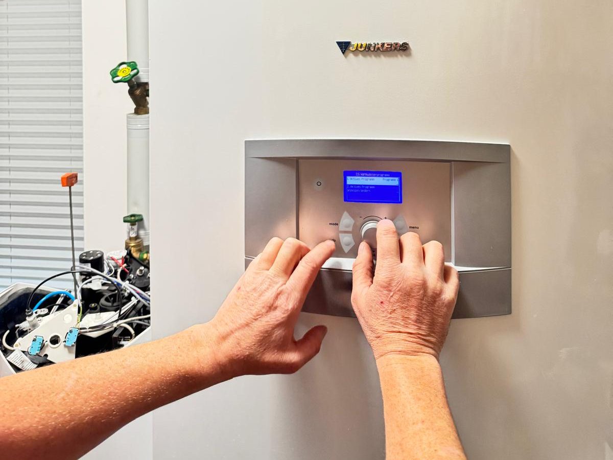 Techniker bedient die Regelung einer Heizungsanlage beim Kundendienst